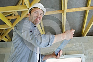 happy male builder on roof wooden-frame-house
