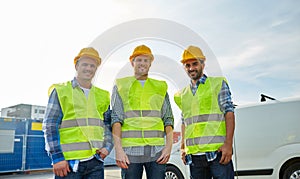 Happy male builders in high visible vests outdoors