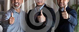 Happy male business professionals, employees, executives, leaders showing thumbs up