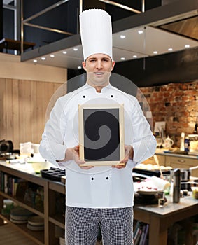 Happy male chef cook holding blank menu board