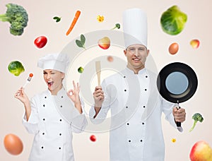 Happy male chef holding frying pan and spatula