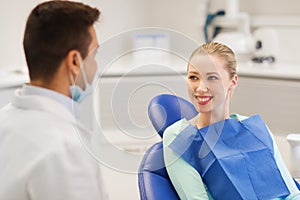 Happy male dentist with woman patient at clinic