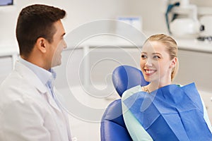 Happy male dentist with woman patient at clinic