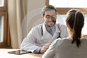 Happy male doctor consult female patient in clinic