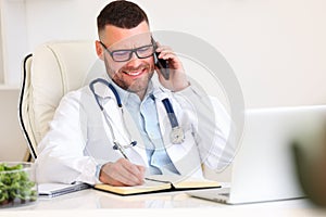 Happy male doctor consulting patient by phone call while working in hospital