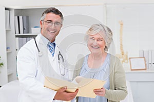Happy male doctor and female patient with reports