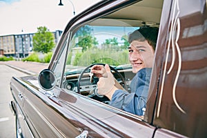 Happy male driver showing keys in open car window