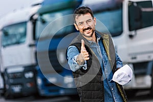 Happy male driver standing in front of his truck