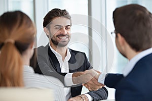 Happy male employee handshaking HR managers after good interview