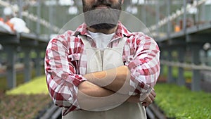 Happy male farmer folding arms looking camera, greenhouse business, agronomy