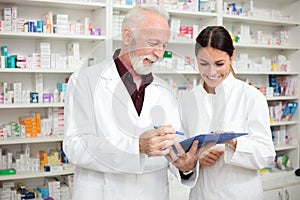 Happy male and female pharmacists holding a clipboard and writing