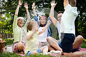 Happy male and female playing and enjoying picnic with children outside
