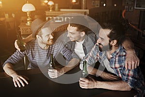 Happy male friends drinking beer at bar or pub