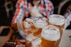 People, men, leisure, friendship and celebration concept - happy male friends drinking beer and clinking glasses at bar or pub