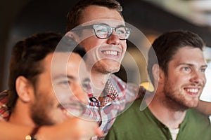 Happy male friends watching football at bar or pub