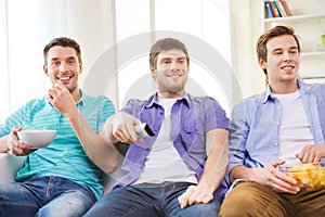 Happy male friends watching tv at home