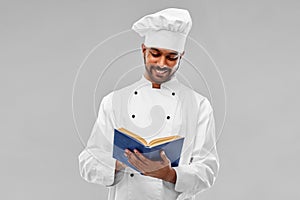 Happy male indian chef reading cookbook