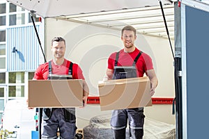 Happy Male Movers Holding Cardboard Boxes