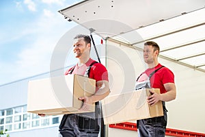 Happy Male Movers Holding Cardboard Boxes