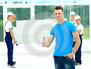 Happy male movers in uniform carrying