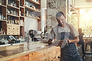 Happy male owner of cafe using digital tablet