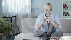 Happy male pensioner sitting on couch at rehabilitation center, recovery period