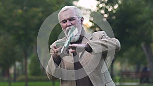 Happy male pensioner throwing around dollar bills, lottery luck, investment