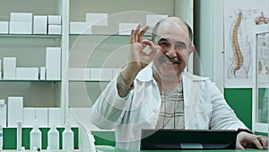 Happy male pharmacist showing allright sign and stumb up smiling