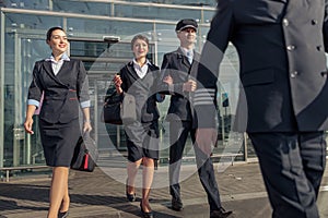 Happy male pilots and two stewardesses leaving the airport terminal