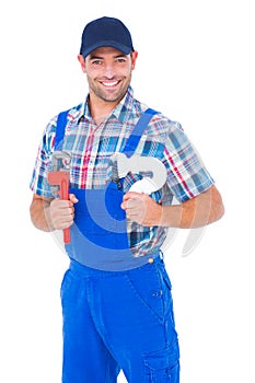 Happy male plumber holding monkey wrench and sink pipe