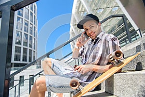 Happy male skateboarder talking on smartphone
