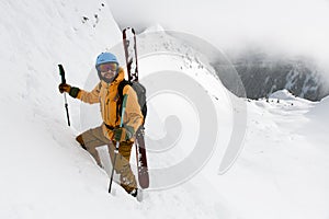 happy male skier with skitour equipment is climbing the snowy hill photo