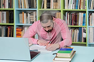 Happy Male Student Working With Laptop In Library