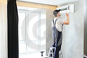 Happy Male Technician Repairing Air Conditioner.