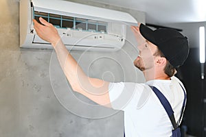 Happy Male Technician Repairing Air Conditioner.