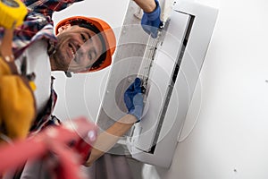 Happy Male Technician Repairing Air Conditioner With Screwdriver