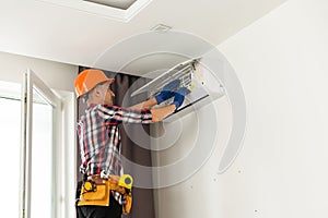 Happy Male Technician Repairing Air Conditioner With Screwdriver
