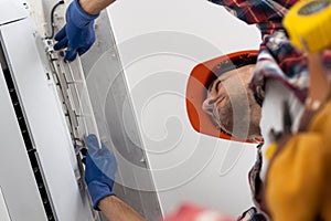 Happy Male Technician Repairing Air Conditioner With Screwdriver