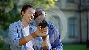 Happy male teenager showing smartphone application to father sitting outdoors