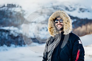 Happy male tourist smiling in nature on a mountain during an active holiday vacation.Hiker on a winter trek.Ski season, extreme