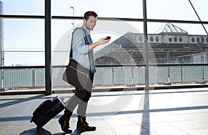 Happy male traveler walking with bags and cellphone