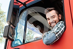 Happy male truck driver inside his red cargo truck