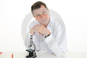 Happy male wearing lab coat while sitting in clinic