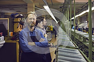 Happy male worker standing in shoe manufacturing workshop at footwear making factory