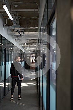 Happy male worker walking down corridor indoors