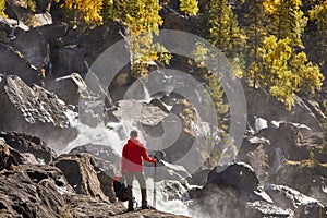 Happy man with backpack enjoying amazing waterfall Travel Lifestyle and success concept vacations into the wild nature