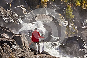 Happy man with backpack enjoying amazing waterfall Travel Lifestyle and success concept vacations into the wild nature