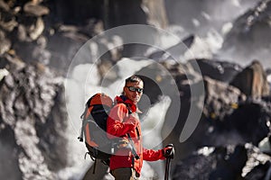 Happy man with backpack enjoying amazing waterfall Travel Lifestyle and success concept vacations into the wild nature