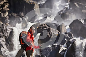 Happy man with backpack enjoying amazing waterfall Travel Lifestyle and success concept vacations into the wild nature