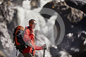 Happy man with backpack enjoying amazing waterfall Travel Lifestyle and success concept vacations into the wild nature